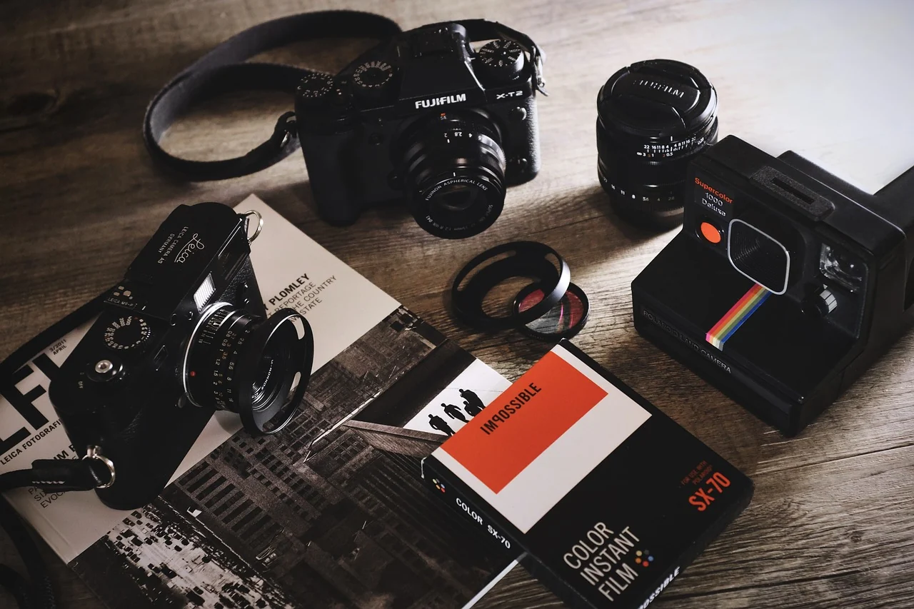 Cameras, a separate lens, accessories and instant-film boxes on a wooden table
